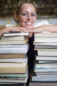 Portrait of female librarian with stacked books